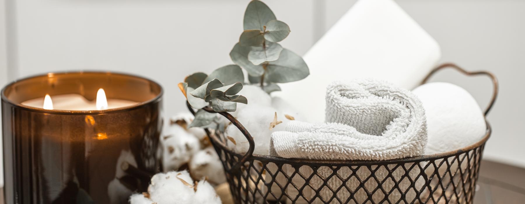 a candle beside cotton and a basket of towels